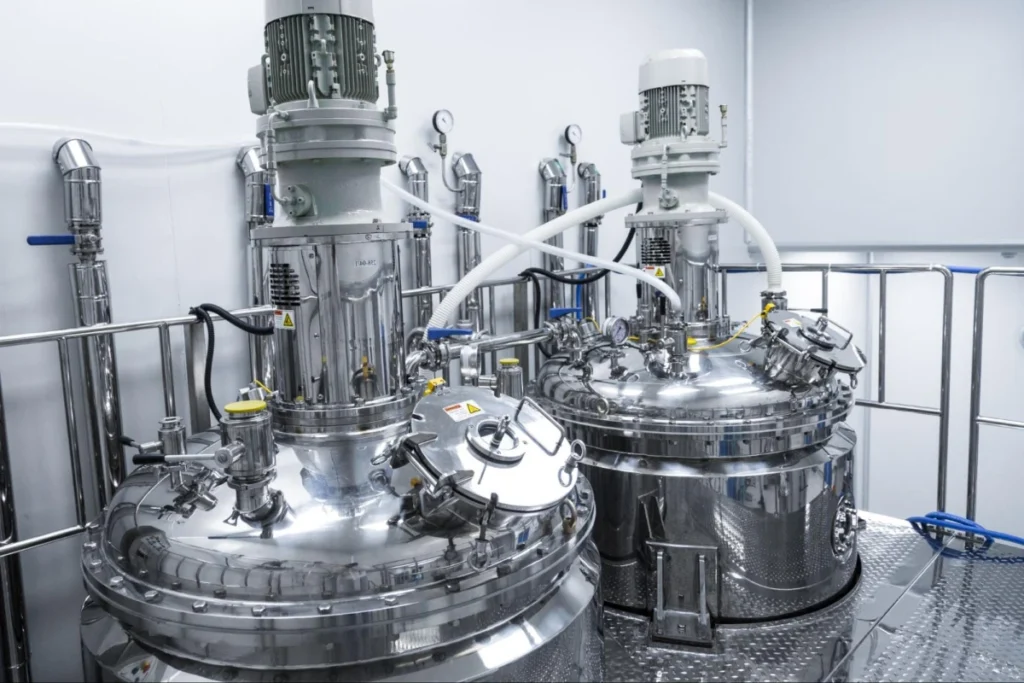 Paired stainless steel mixing tanks in a facility.